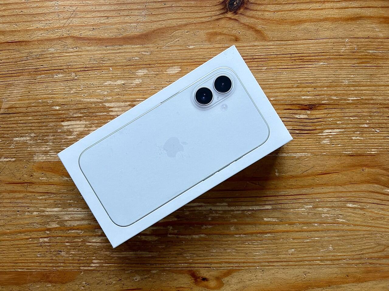 放在木桌上、尚未拆封的白色 iPhone 16 包裝盒